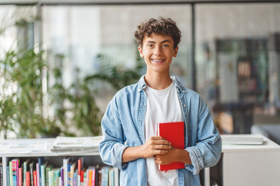 Smiling young man holding a book, representing community involvement